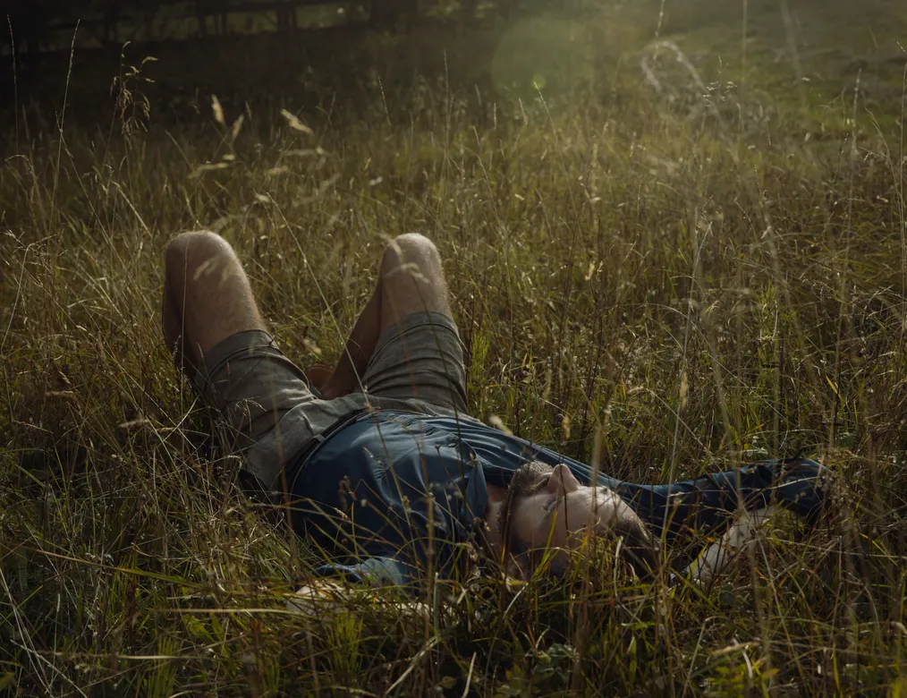 Man lying relaxed in golden alpine grass at Ehrwald – summer tranquility and letting go in nature near eriro Alpine Hide at Zugspitze