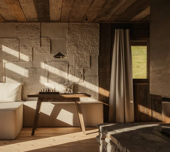 Handcrafted wool patchwork wall with chess set in sunlit living area – alpine craftsmanship meets design at eriro Alpine Hide
